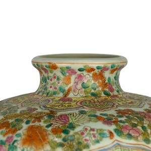 May include: A large, white porcelain vase with a wide mouth and a floral design. The vase is decorated with a variety of flowers in shades of pink, red, yellow, and green. The flowers are arranged in a symmetrical pattern around the vase.