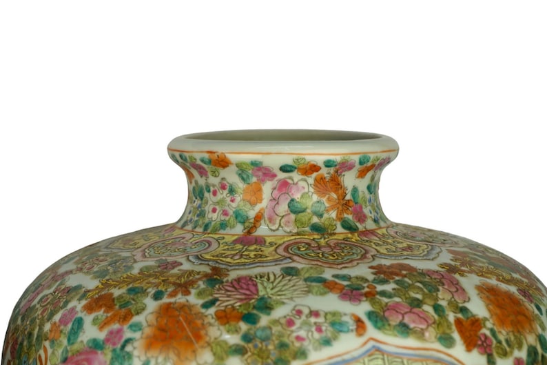 May include: A large, white porcelain vase with a wide mouth and a floral design. The vase is decorated with a variety of flowers in shades of pink, red, yellow, and green. The flowers are arranged in a symmetrical pattern around the vase.