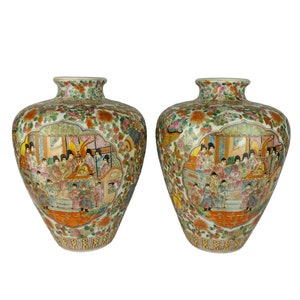 May include: Two large, white porcelain vases with intricate floral and figural designs in shades of green, orange, pink, and blue. The vases feature a scene of people in traditional Chinese clothing.