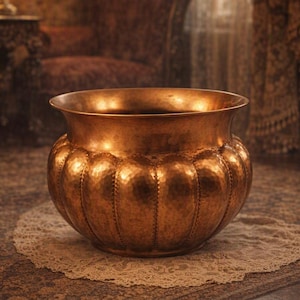 May include: A round, metallic copper-coloured planter with a wide, flared rim and a bulbous body. The surface features a distinct hammered texture with vertical, indented ribs that create a segmented, rounded appearance around the entire vessel.