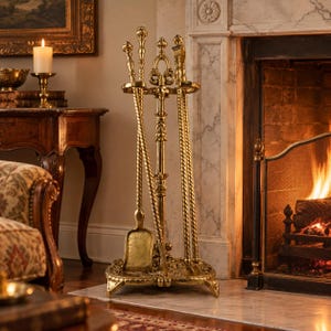 May include: A gold-toned metal fireplace tool set featuring a central stand with a decorative base, holding a shovel, a poker, and a pair of tongs. Each tool has a twisted handle and a matching finial, arranged vertically in a circular holder.