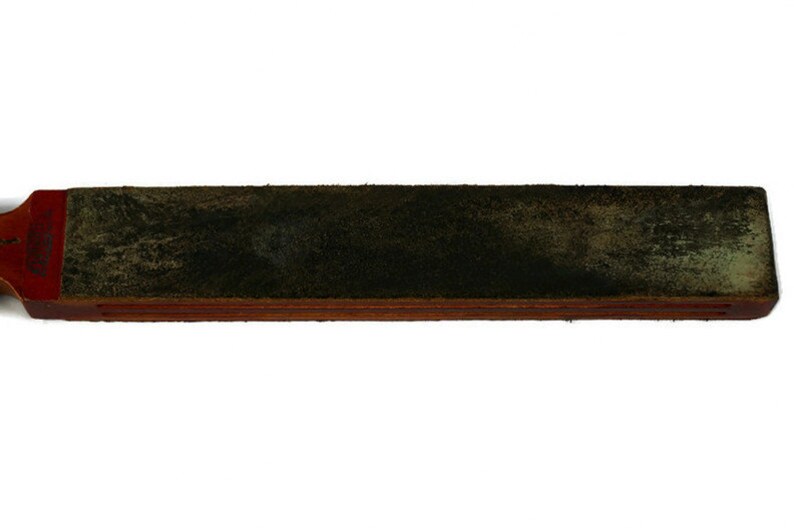 May include: A dark green leather strop with a wooden base. The strop is used to sharpen straight razors.