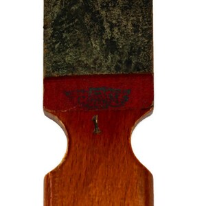 May include: A wooden sharpening tool with a red and green surface. The tool has a number "1" printed on it. The text "The Best" is printed on the red surface.