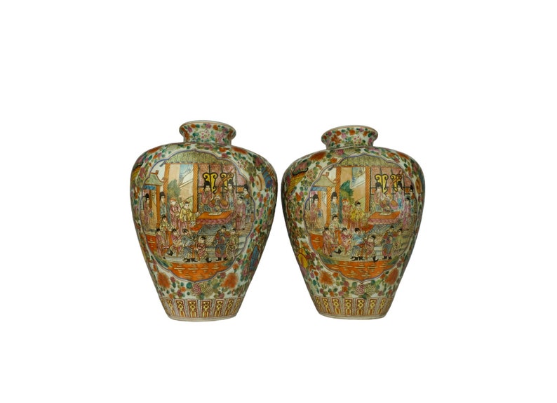 May include: Two porcelain vases with a white background and intricate floral and geometric designs in shades of green, orange, and pink. The vases feature a scene of people in traditional clothing.