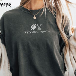 May include: Dark gray sweatshirt with the text "My year...again" and a graphic of a football and trophy. The sweatshirt is a comfortable, casual style.
