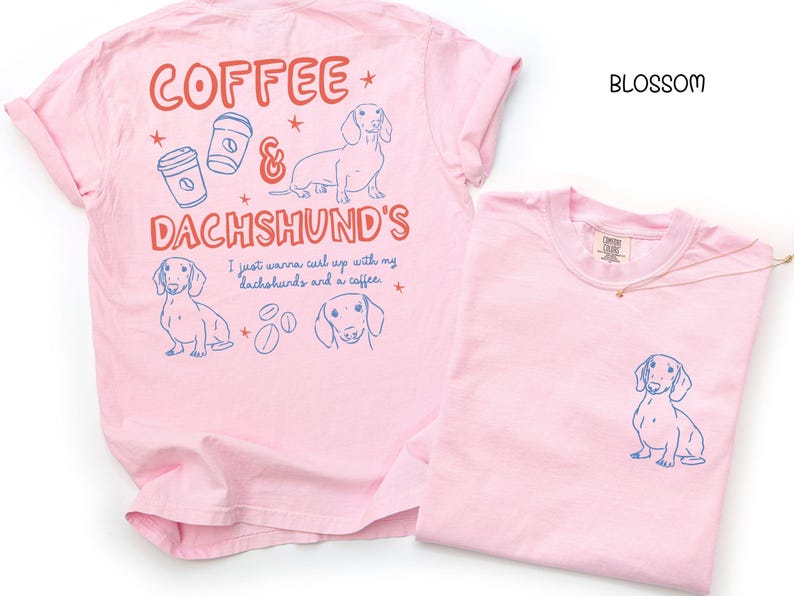 May include: Two light pink t-shirts. One has a dachshund graphic on the pocket. The other has a dachshund graphic, coffee cups, and the words "Coffee & Dachshund's" in red and blue. The text "I just wanna curl up with my dachshunds and a coffee" is also present.