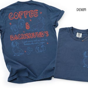 May include: Two denim blue t-shirts. One shirt has the text "COFFEE & DACHSHUND'S" with illustrations of coffee cups, stars, and dachshunds. The other shirt has a dachshund illustration. The word "DENIM" is printed in black.