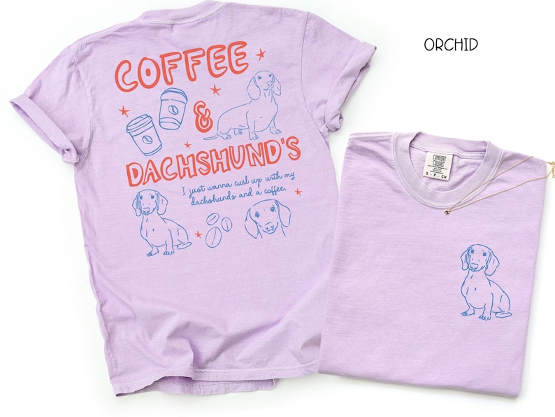 May include: Orchid-colored t-shirts with dachshund and coffee-themed graphics. One shirt features a large design on the back with text and illustrations, while the other has a small dachshund graphic on the front pocket.