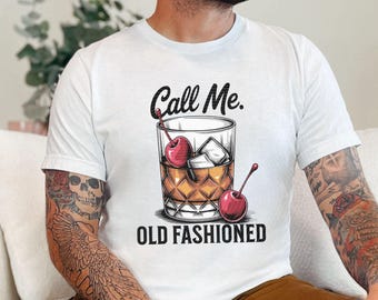 May include: White t-shirt with a graphic of a glass of whiskey with cherries and the text "Call Me. Old Fashioned."