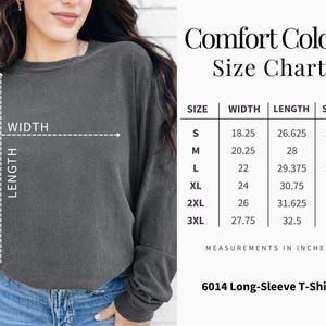 May include: A dark gray long-sleeve t-shirt with a size chart. The chart lists measurements in inches for width, length, and sleeve length for sizes S through 3XL. The shirt is labeled as a 6014 Long-Sleeve T-Shirt.