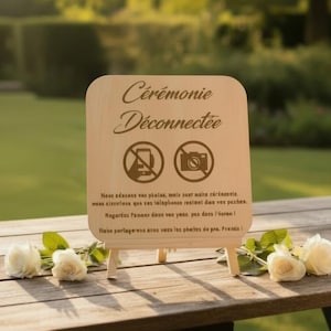 Peut inclure: Panneau en bois avec l'inscription "Cérémonie Déconnectée" et des symboles d'interdiction de téléphones et d'appareils photo. Le panneau est sur un petit chevalet, avec des roses blanches.