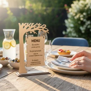 Peut inclure: Un porte-menu en bois clair en forme d'arbre avec un panneau rectangulaire suspendu à ses branches. Le panneau affiche le texte MENU, En entrée: planches apéritives, En plat principal: salade chic, accompagné de légumes fins et toasts, En dessert: un assortiment de tartes aux fruits et des fruits frais.