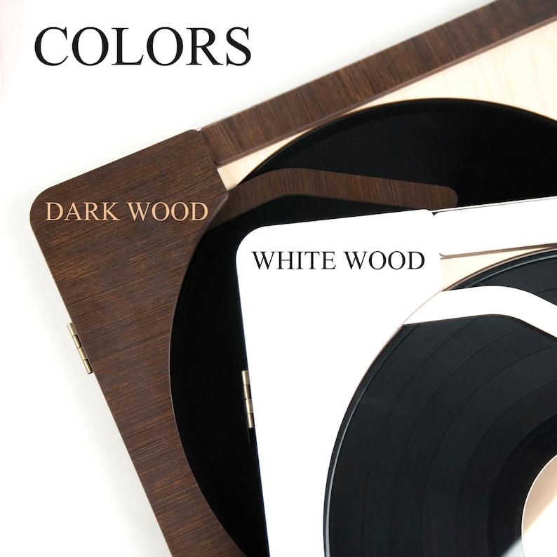May include: A wooden record player with a black vinyl record. The player is available in two colors: dark wood and white wood. The text "COLORS" is displayed at the top of the image. The text "DARK WOOD" is displayed on the dark wood side of the player. The text "WHITE WOOD" is displayed on the white wood side of the player.