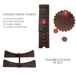 May include: Wooden stand for a katana sword, consisting of four parts: an acrylic front panel, a wooden back panel, a wooden stopper, and a wooden and leather part. The stand is made of dark brown wood and has a simple, elegant design.  The stand is labeled "WOODEN STAND IN SET".
