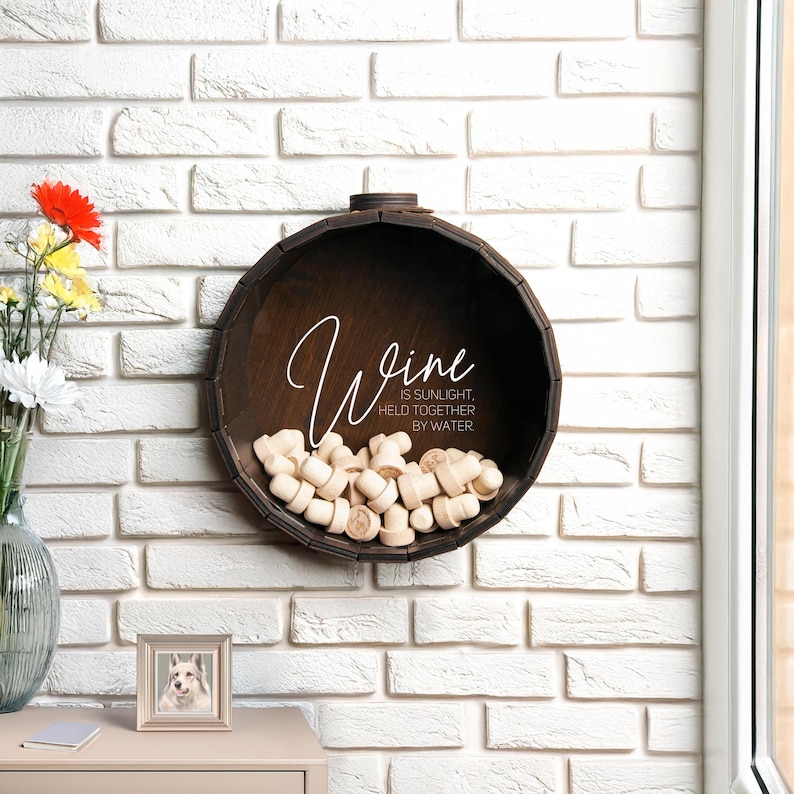 May include: A wooden wine barrel with a cork holder and the text "Wine is sunlight held together by water".