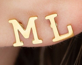 Puede incluir: Pendientes de iniciales de oro con las letras "M" y "L" en el lóbulo de una oreja.