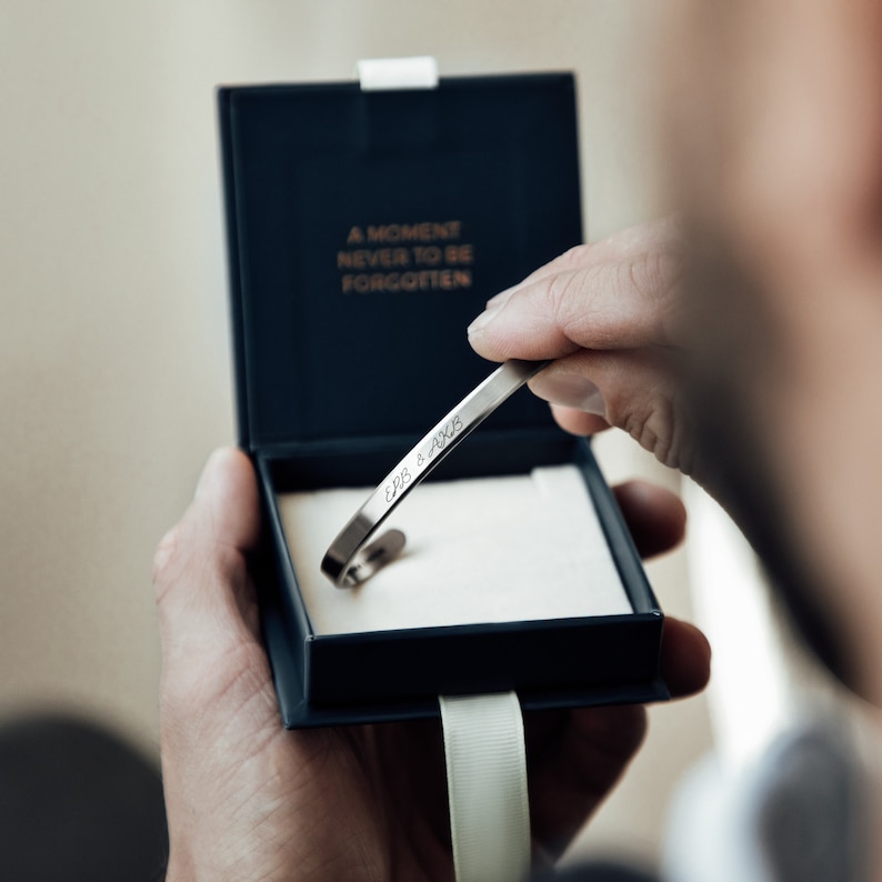 May include: A silver bangle bracelet with the inscription "2013 & 2015" and the words "A moment never to be forgotten" on the box.