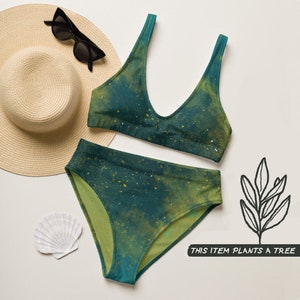 Peut inclure: Un maillot de bain deux pièces dans des tons vert foncé et olive avec un motif éclaboussé. L'ensemble comprend un haut à encolure dégagée et un bas taille haute. Un chapeau de paille, des lunettes noires et un coquillage accompagnent le texte THIS ITEM PLANTS A TREE.