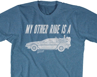 Könnte beinhalten: Blaues T-Shirt mit dem Text "MY OTHER RIDE IS A" und einer weißen Umrisszeichnung eines DeLorean-Autos aus dem Film Zurück in die Zukunft. Das T-Shirt hat einen Rundhalsausschnitt.