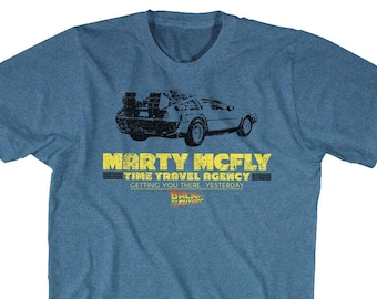 Könnte beinhalten: Ein blaues T-Shirt mit einem Motiv der DeLorean-Zeitmaschine aus dem Film Zurück in die Zukunft. Der Text auf dem Shirt lautet "Marty McFly Time Travel Agency Getting You There Yesterday".