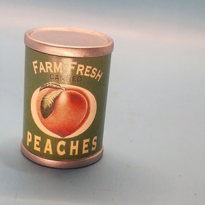 May include: A silver can of canned peaches with a green label that says "Farm Fresh Canned Peaches" and a picture of a peach.