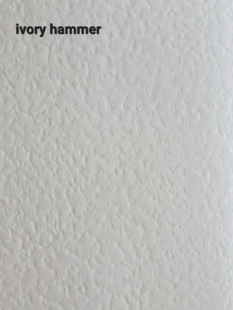 May include: Textured ivory-coloured surface with the words "ivory hammer" in a dark font at the top. The surface has a rough, uneven appearance, with a subtle, off-white hue.