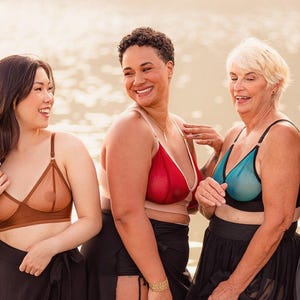 Può includere: Tre persone indossano reggiseni trasparenti in diversi colori e stili. Sono in piedi insieme e sorridono. La donna a sinistra indossa un reggiseno marrone, la donna al centro indossa un reggiseno rosso e la donna a destra indossa un reggiseno blu.