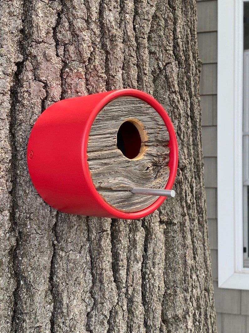 Unique stylish architectural designed wall mounted birdhouse gives birds a cozy home in vibrant poppy red color. The juxtaposition of salvaged 100-year-old vintage barn wood capping a modern angled vinyl tube adds functional art to any yard or garden