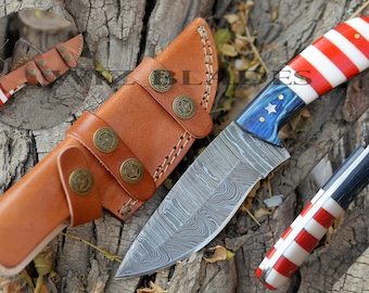 May include: A handmade Damascus steel knife with a blue and white patterned handle and a red, white, and blue patterned sheath. The knife has a leather sheath with brass accents.