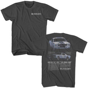 Op de afbeelding: Een donkergrijs T-shirt met een vintage afbeelding van een blauwe Shelby G.T. 350 auto. De tekst "SHELBY G.T. 350 "THE ROAD CAR" FOR THE MAN WHO WANTS EVERYTHING IN HIS CAR" staat op het shirt gedrukt.