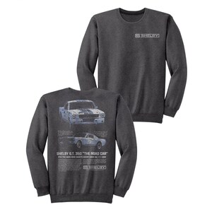 Op de afbeelding: Een donkergrijs sweatshirt met lange mouwen met een vintage illustratie van een blauwe en witte Shelby GT 350 auto. De tekst "SHELBY G.T. 350 "THE ROAD CAR" FOR THE MAN WHO WANTS EVERYTHING IN HIS CAR" is op het sweatshirt gedrukt. Het woord "SHELBY" is in wit op de voorkant van het sweatshirt gedrukt.