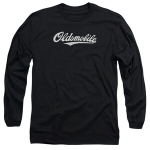 Pu&ograve; includere: Maglietta a maniche lunghe nera con un logo "Oldsmobile" bianco in stile vintage.