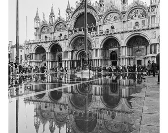 Puede incluir: Una fotografía en blanco y negro de un gran edificio adornado con un reflejo en un charco de agua frente a él.