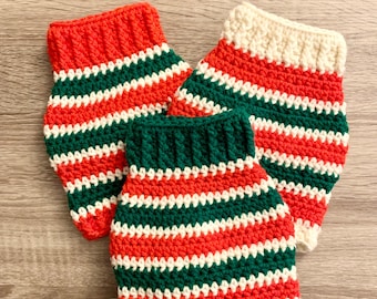 May include: Three crocheted striped leg warmers in red, white, and green.