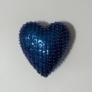 Op de afbeelding: Een blauwe hartvormige versiering bedekt met pailletten.