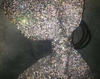 May include: A silver sparkly bow hair clip with a black elastic band.