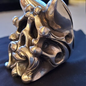 Può includere: Un anello a forma di teschio in argento con dettagli intricati e una superficie testurizzata.