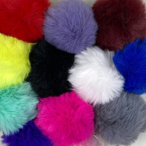 以下が含まれることがあります： 12色のふわふわしたポンポンキーホルダーの詰め合わせ。キーホルダーは柔らかくふわふわした素材で作られており、赤、紫、黒、白、緑、青、黄、ピンク、グレーなど、さまざまな色があります。