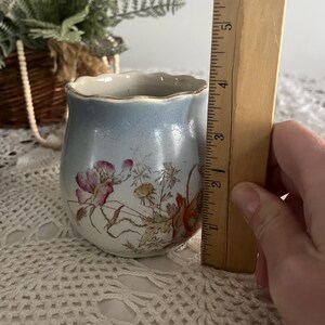Pu&ograve; includere: Un piccolo vaso in ceramica blu e bianco con un bordo ondulato. Il vaso &egrave; decorato con un motivo floreale in tonalit&agrave; di rosa, rosso e giallo. Il vaso &egrave; alto circa 10 cm.