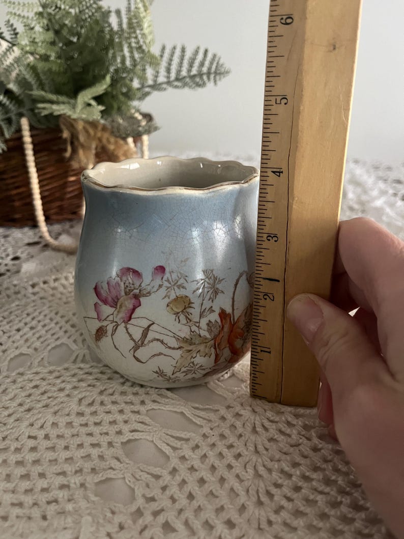 Pu&ograve; includere: Un piccolo vaso in ceramica blu e bianco con un bordo ondulato. Il vaso &egrave; decorato con un motivo floreale in tonalit&agrave; di rosa, rosso e giallo. Il vaso &egrave; alto circa 10 cm.