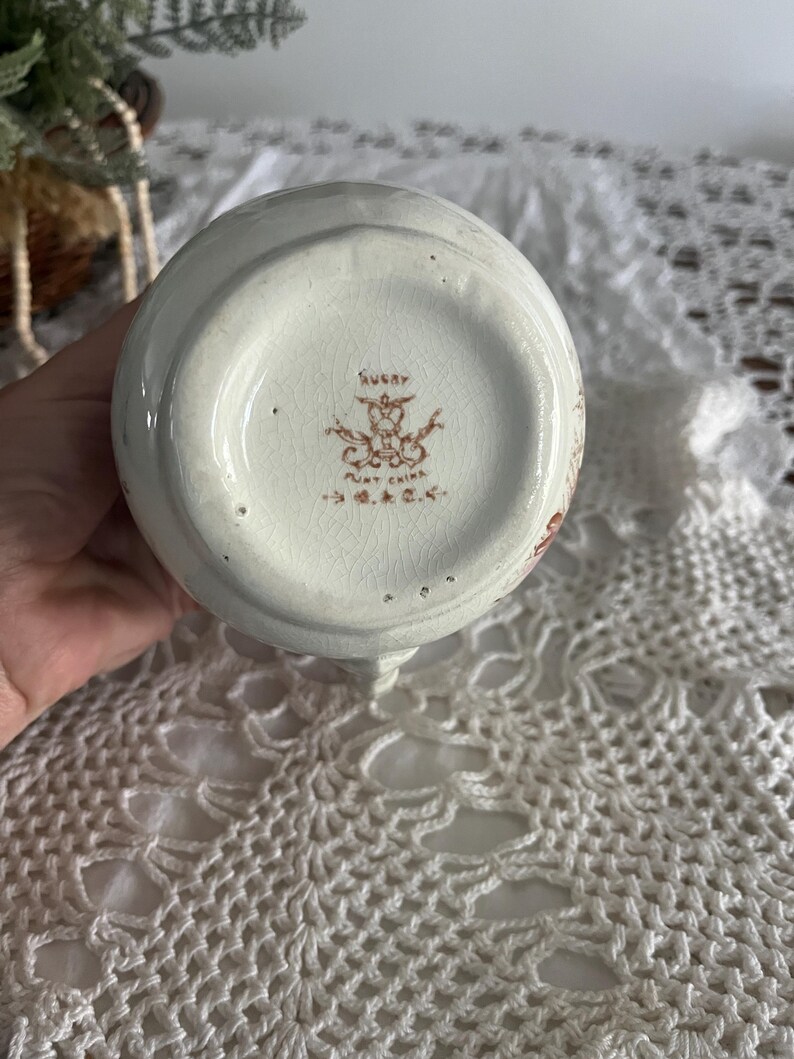 Pu&ograve; includere: Brocca in ceramica bianca con un motivo floreale marrone e un marchio marrone sul fondo che recita "Rugby Aunt China G&C."
