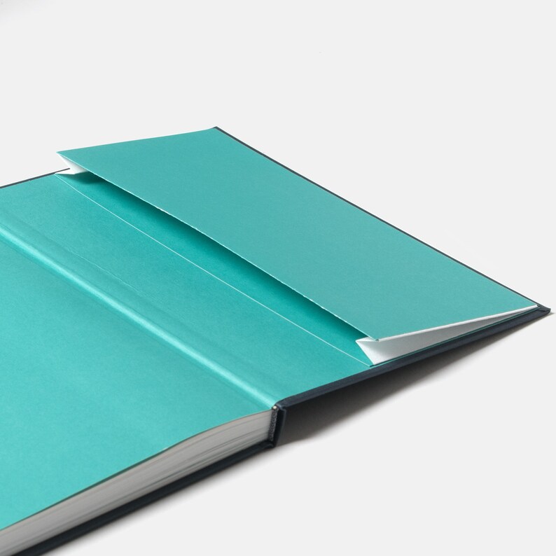 May include: A teal blue hardcover journal with a built-in pocket on the inside cover.