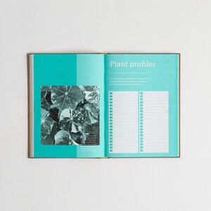 Pu&ograve; includere: Un libro aperto con una copertina blu turchese e una foto in bianco e nero di foglie. La pagina destra ha il titolo "Profili delle piante" e un elenco di informazioni sulle piante.