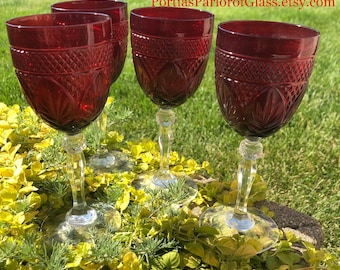 May include: Set of four ruby red wine glasses with a cut glass design. The glasses have a clear stem and base.