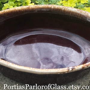 Peut inclure: Un plat à four ovale en céramique émaillée brun et blanc. Le plat est vide et a une finition brillante.