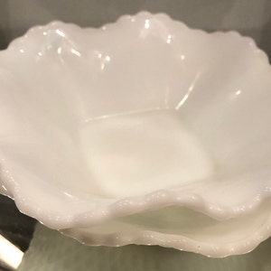 Può includere: Due ciotole in vetro di latte bianco con bordi a festoni. Le ciotole sono impilate l'una sull'altra.