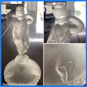 May include: A frosted glass figurine of a young boy holding a bird in his hand. The figurine is on a round base with a frosted glass design of a dog's head.