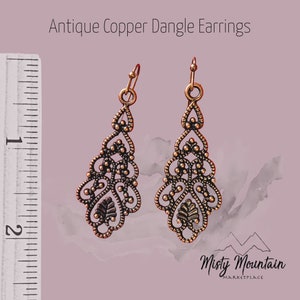 May include: Antique copper dangle earrings with a delicate filigree design. The earrings are approximately 2 inches long.