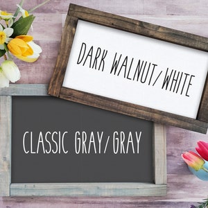 Op de afbeelding: Twee houten borden met verschillende verfkleuren en tekst. Het bovenste bord is donkerwalnoot met witte tekst die "DARK WALNUT/WHITE" luidt. Het onderste bord is klassiek grijs met grijze tekst die "CLASSIC GRAY/GRAY" luidt.