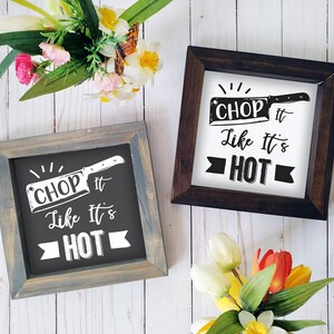 May include: Two wooden framed signs with a black and white graphic of a chef's knife and the text "Chop it like it's hot".